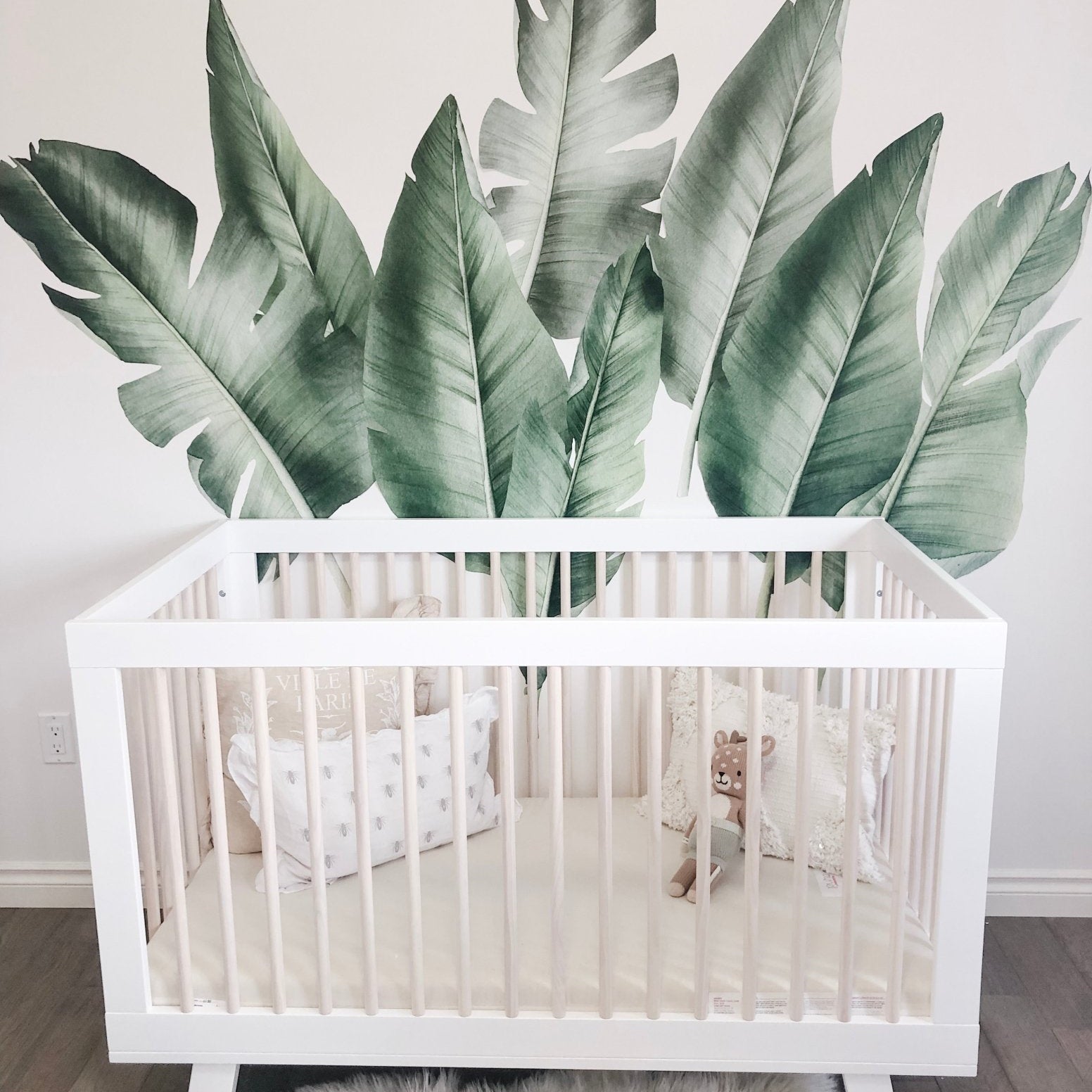 Safari Nursery Decor with giant green tropical leaf wall decals in baby nursery with white crib