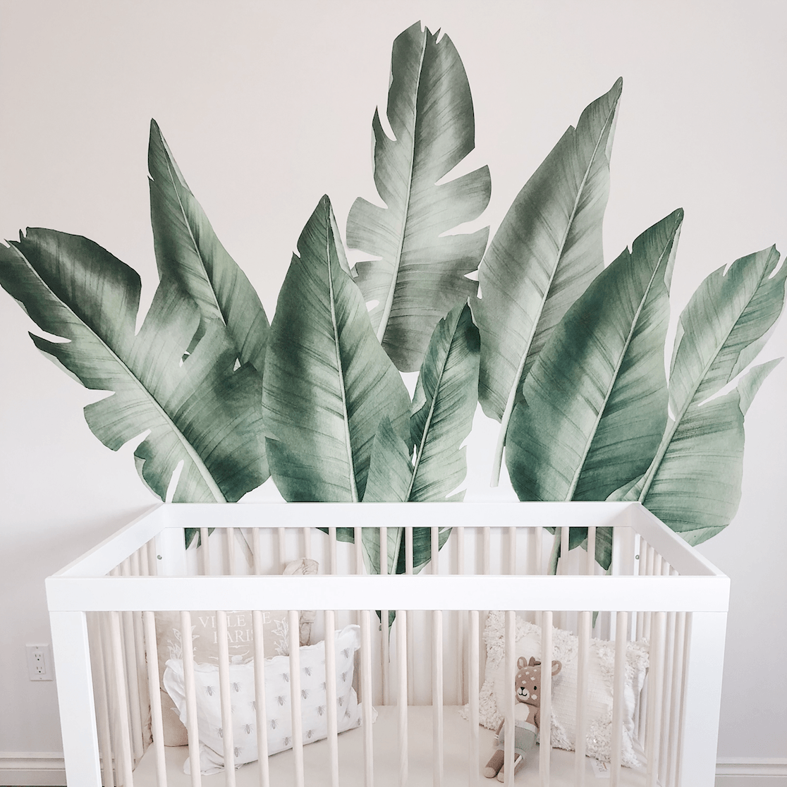 Tropical leaf wall decals for baby boy nursery on white wall with crib