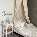 Simplistic child's room with neutral decor and dark green peel and stick wallpaper