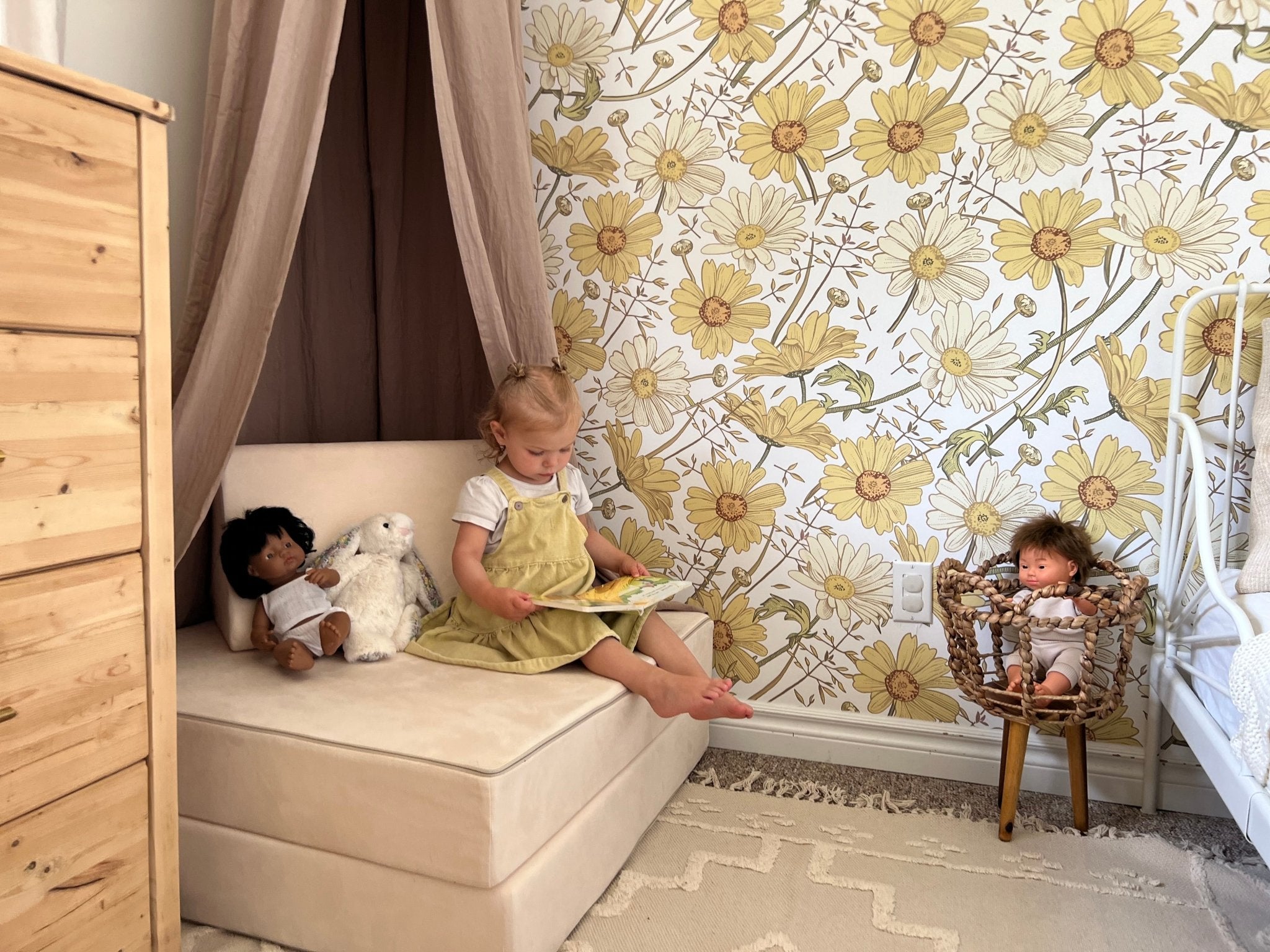 Little girl sits in her bedroom reading a book with beautiful yellow wallpaper and subtle room decor