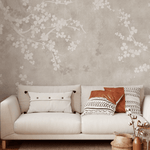 A cozy living space with a beige floral fresco wall mural, cream sofa with decorative pillows, and woven accessories