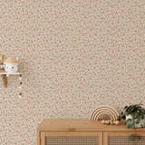 Nursery corner with self-adhesive wallpaper featuring small orange flowers and green leaves.