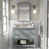 A light-filled bathroom with pastel floral peel and stick wallpaper, a blue vanity, and a pink rug on marble flooring