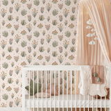 A nursery room featuring walls covered in pastel floral wallpaper, with a white crib and a soft pink canopy.