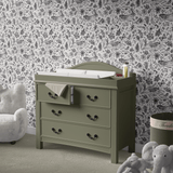 Chic and timeless monochrome peel and stick wallpaper featuring a whimsical pattern of bunnies, flowers, and butterflies, creating an elegant and playful atmosphere in a baby's nursery with a classic green changing table