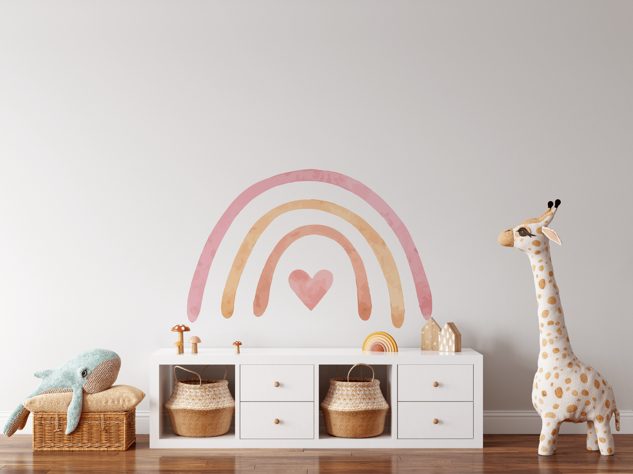 A children's playroom with a pastel rainbow wall sticker above a white dresser. The room has a whimsical feel with a large plush dolphin toy on a wicker bench, a giraffe-shaped toy, and woven baskets for storage.
