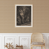 A sophisticated room featuring natural rattan weave wallpaper, a classic wooden chair with rattan detailing, a framed vintage landscape print on the wall, and decorative wicker baskets with pampas grass.