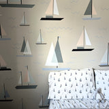 A bedroom with a wall covered in sailboat decals, complementing bedding with a similar pattern, and a plush toy on the bed, creating a serene nautical theme.