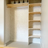 Bedroom closet renovated using natural would accents over a grey and white Scandinavian style peel and still wallpaper