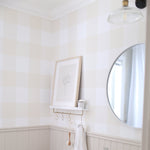 bathroom wallpaper with tan gingham pattern above wood wainscotting with a silver mirror and lamp with a small ledge on wall