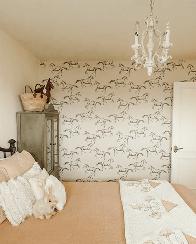 Horse wallpaper in a bedroom with neutral bedding, green armoire and white chandelier. Peel and Stick wild horse wallpaper